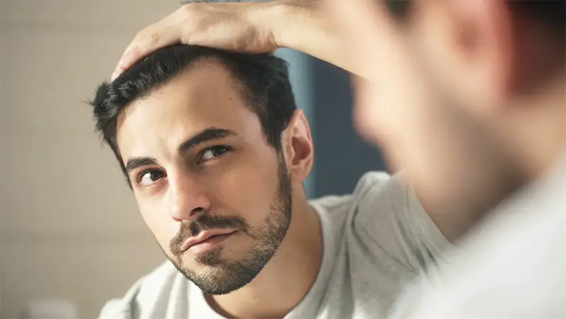 man looking hair at mirror